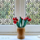 Fountain Decorative Metal Screen Used as a Privacy Window with a bunch of flowers in front of it.